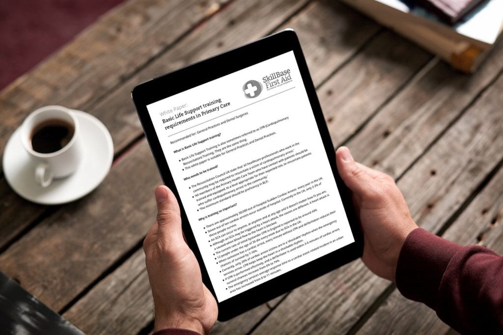 A man holding a tablet with the document "basic life support training requirements in primary care" open on the screen
