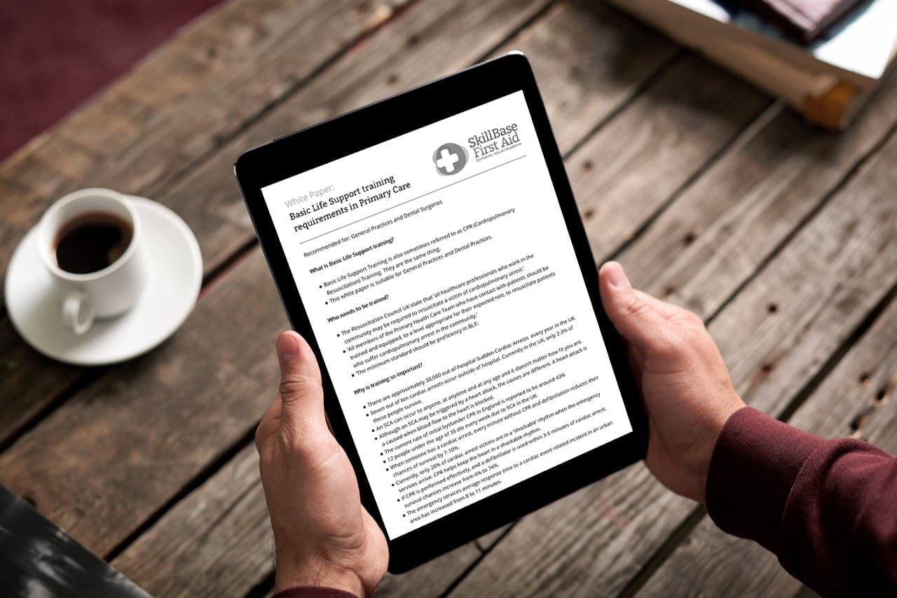 A man holding a tablet with the document "basic life support training requirements in primary care" open on the screen